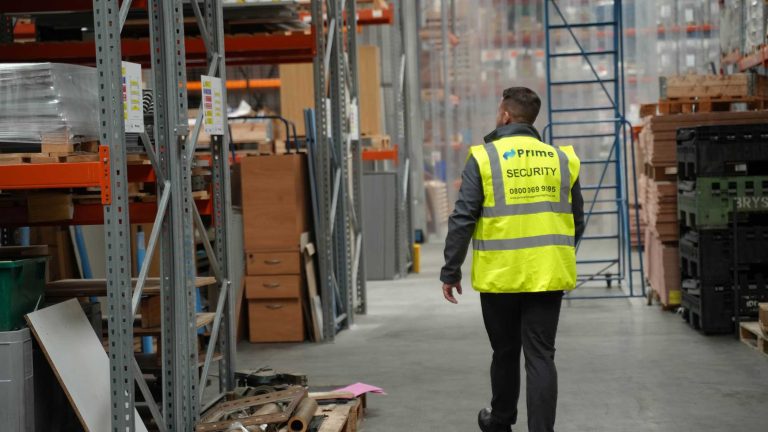 a security guard patrolling the inside of a warehouse, ensuring the site is safe.