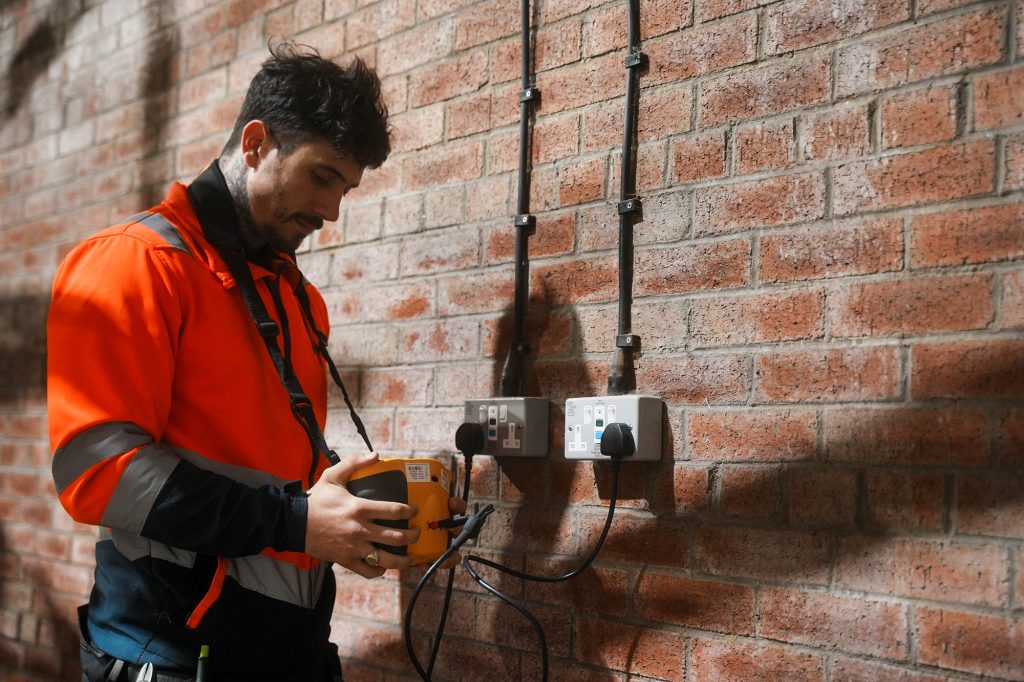 an electrician testing a plug socket for planned preventative maintenance
